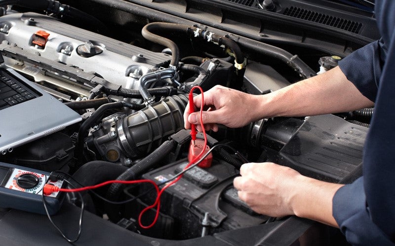 Mechanic at Dan Cummins Chevrolet Buick of Paris dealership recharging a small battery